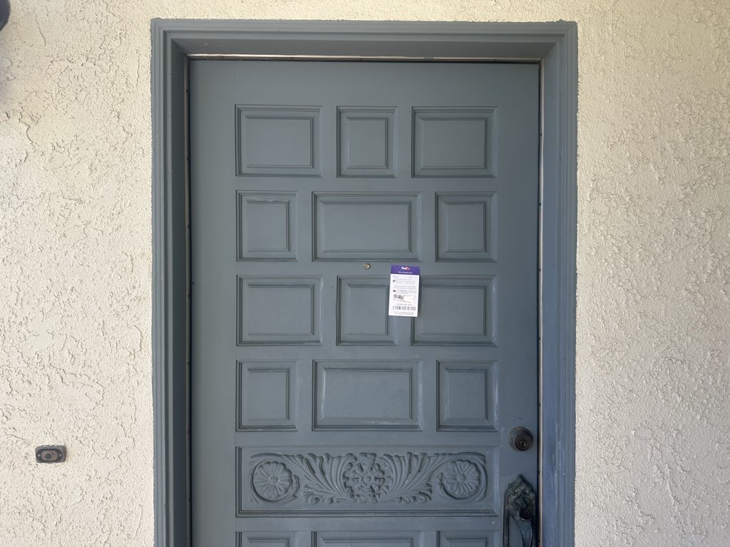 Missed-delivery notice stuck to a gray front door